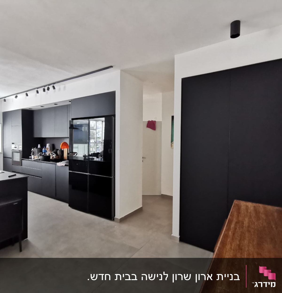 מטבח מודרני עם ארונות שחורים ומשטח עבודה מעץ